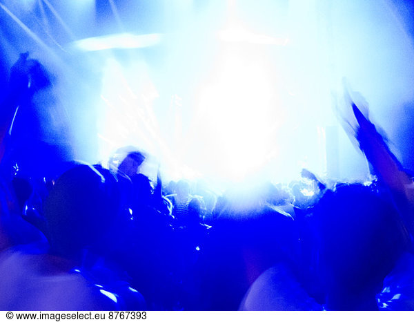 Silhouette of crowd facing illuminated stage