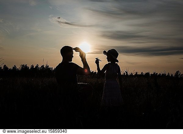 silhouette of father and daughter playing outside with paper aeroplane