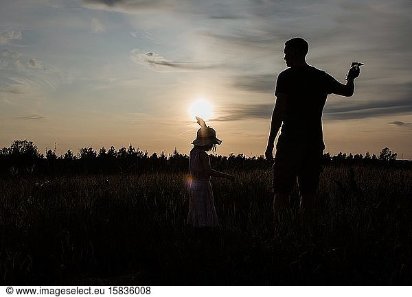 silhouette of father and daughter playing together outside at sunset