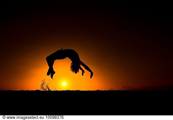 Silhouette of man doing back flip  at sunset  Omakaha  Oahu  Hawaii