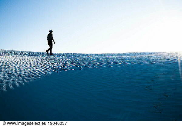 Silhouette of man walking in on dunes