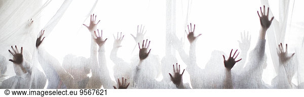 Silhouette of people raising hands behind transparent curtain