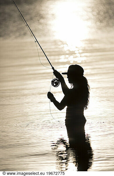 Silhouette of woman fly-fishing