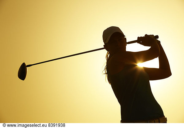 Silhouette of woman playing golf on course