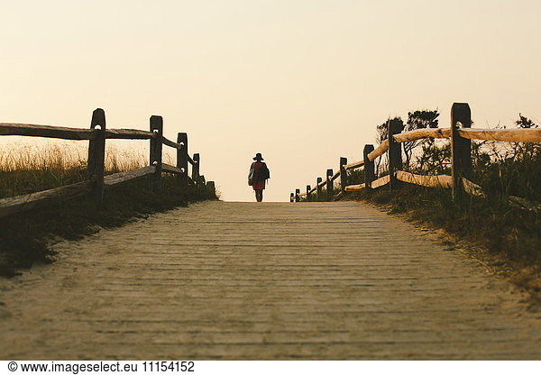 Silhouette of woman walking on wooden walkway