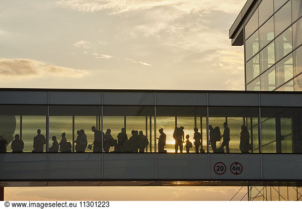 Silhouette people walking in airport sky bridge
