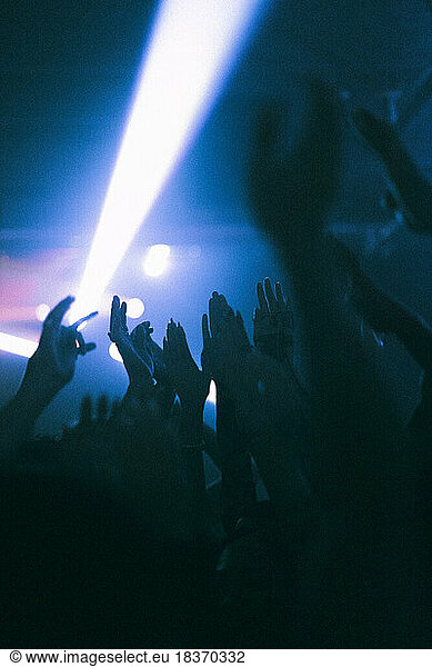 Silhouette raised hands of women and men dancing at nightclub