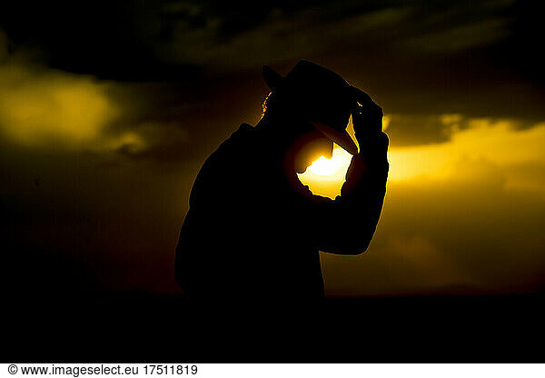 Silhouette senior man wearing hat during sunset