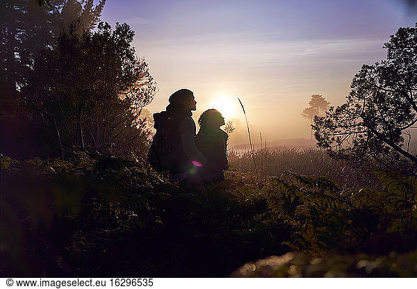 Silhouette serene young couple enjoying hike in nature at sunset
