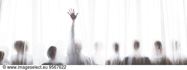 Silhouette von Menschen hinter transparentem Vorhang  eine Person hebt die Hand