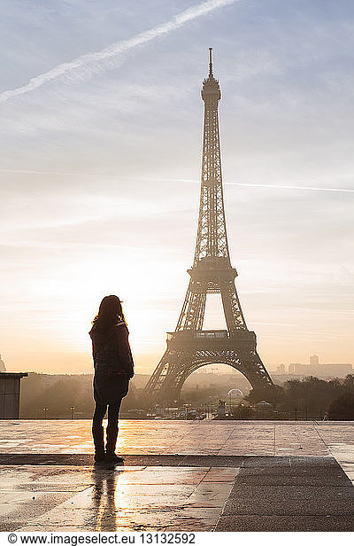 Silhouette woman looking at Eiffel Tower against sky