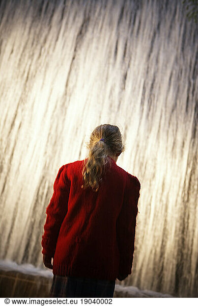 Silhouetted person in front of a waterfall fountain.