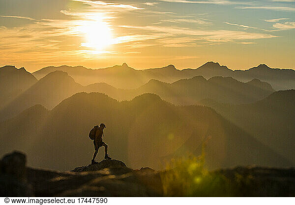 Silhouetted view of backpacker hiking on mountain summit.