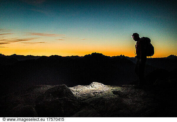 Silhouetted view of backpacker on mountain summit.
