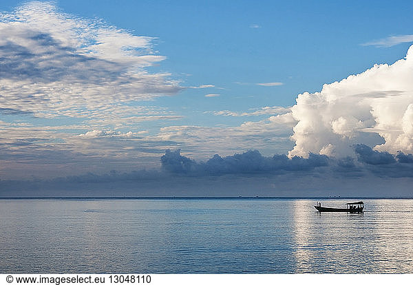 Silhouettenboot segelt im Meer gegen bewölkten Himmel