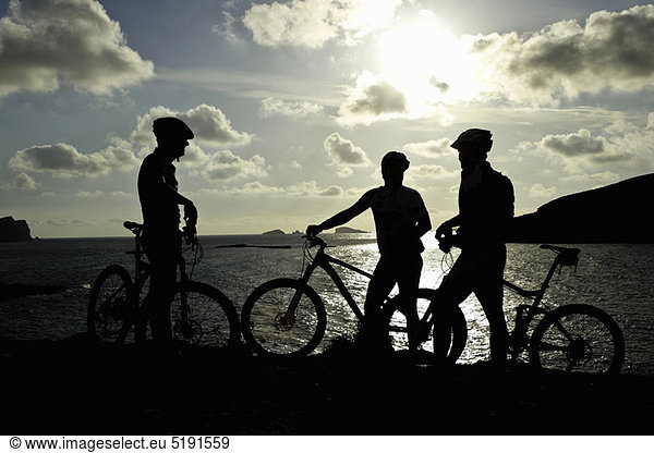 Silhouettes of mountain bikers by lake