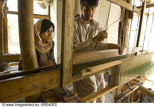 Silk weaver shows a customer the loom where the cloth she purchases is made.
