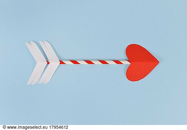 Simple paper cupid love arrow with heart shaped tip on blue background