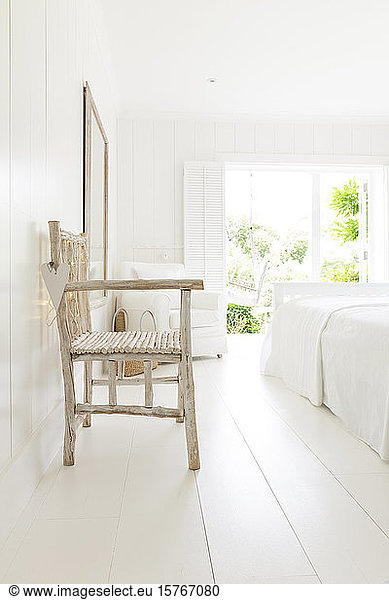 Simple wood armchair in white beach house bedroom