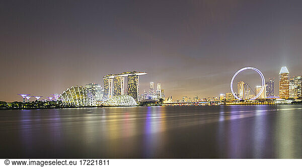 Singapur  Langzeitbelichtung von Marina Bay bei Nacht mit Marina Bay Sands Hotel und Singapore Flyer im Hintergrund