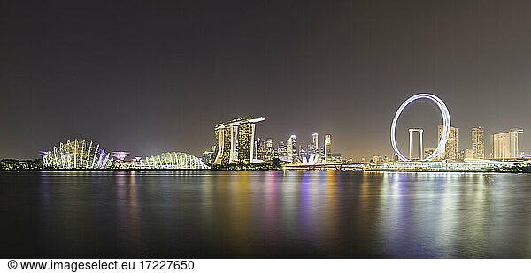 Singapur  Langzeitbelichtung von Marina Bay bei Nacht mit Marina Bay Sands Hotel und Singapore Flyer im Hintergrund