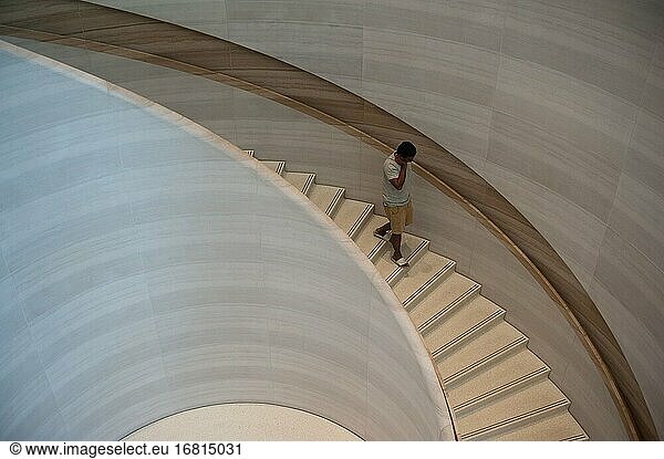 Singapur  Republik Singapur  Asien - Ein Kunde geht eine geschwungene und skulpturale Treppe im ersten Apple Store Singapurs in der Knightsbridge Mall an der Orchard Road hinunter. Das Gebäude wurde von dem englischen Architekten Norman Foster (Foster and Partners) entworfen.