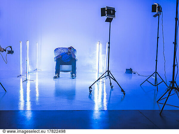 Singer sitting on chair filming at studio