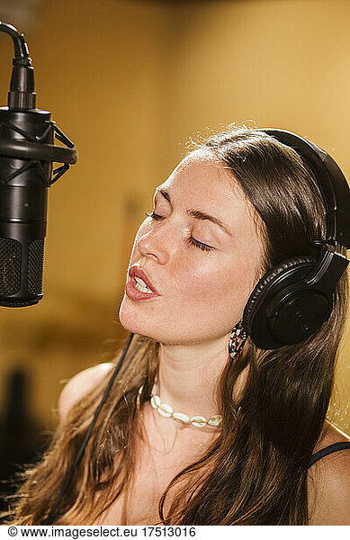 Singer with headphones at microphone in recording studio