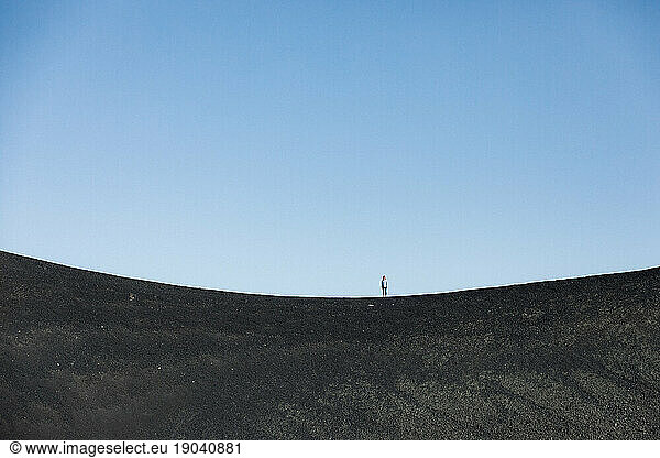 single female stands alone on a volcanic rim of craters of the moon