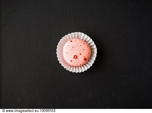 Single macaron against black background  overhead view