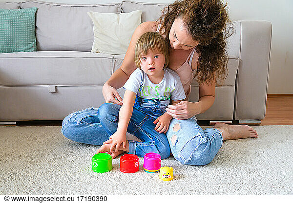 Single mother is playing with her disabled child in their appart