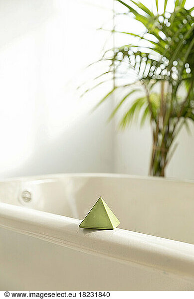 Single pyramid shaped toy block lying on bathtub rim