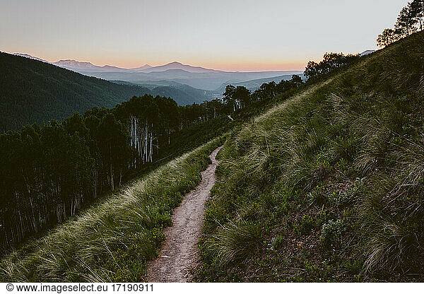Single Track Trail mit Bergen im Hintergrund bei Sonnenuntergang