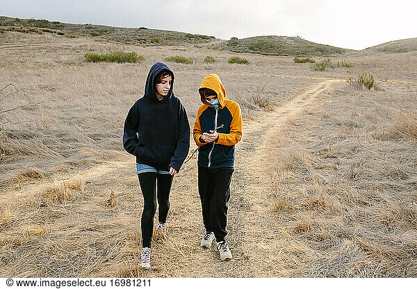 Sister And Brother Walk Along A Hiking Trail In Southern California
