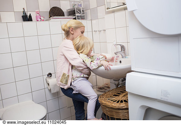 Sister helping girl in washing hand