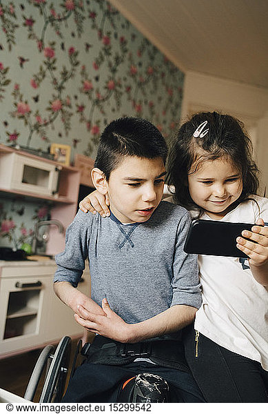 Sister showing video to autistic brother on smart phone at home