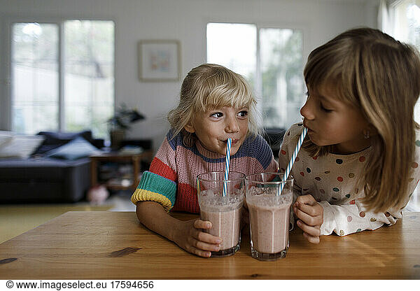 Sisters drinking smoothie looking at each other