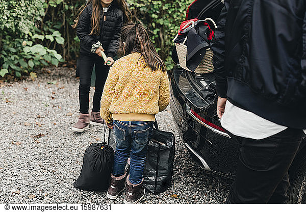 Sisters loading luggage in electric car while going for picnic at weekend