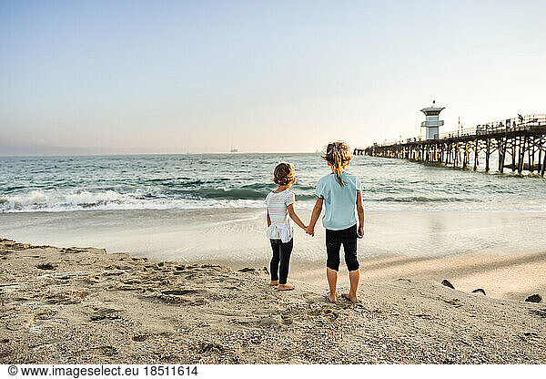 Sisters looking at ocean holding hands
