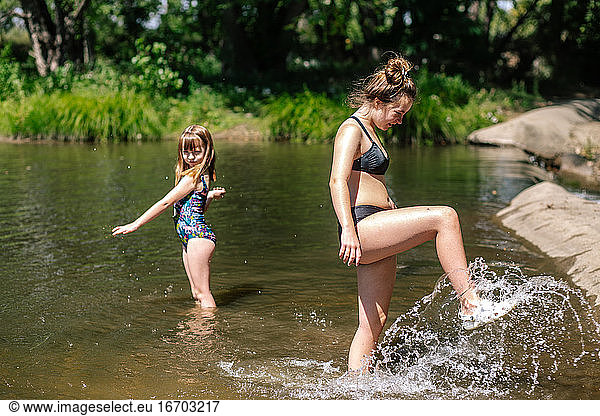 Sisters playing and splashing in a river on a sunny day