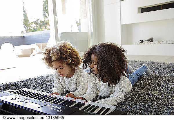 Sisters playing keyboard instrument at home