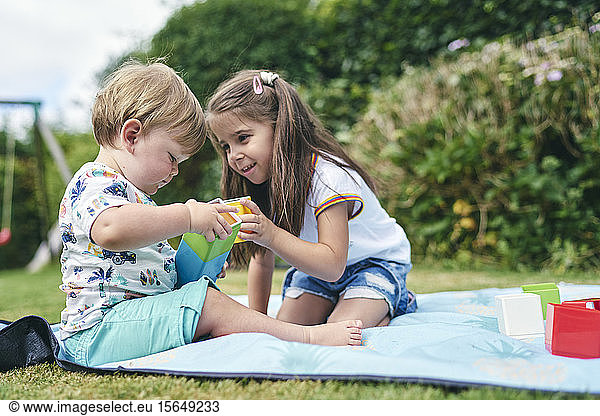 Sisters playing with blocks on picnic blanket
