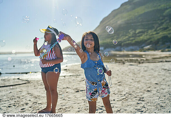 Sisters playing with bubbles on sunny beach