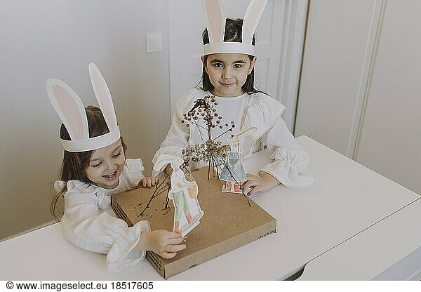 Sisters wearing rabbit ears doing decorations for Easter at home