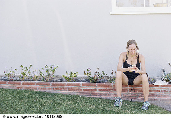sitzend blond Frau ruhen Wand Sportkleidung Garten joggen