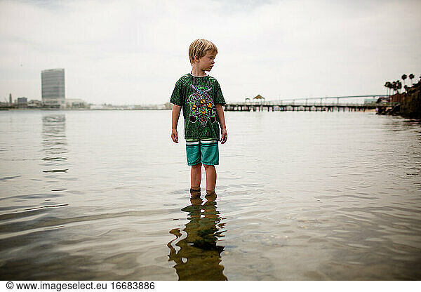 Six Year Old Boy Standing in Coronado Bay with Pier in Background