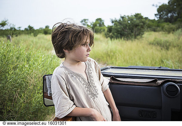 Six year old boy standing looking around the landscape in a safari jeep.