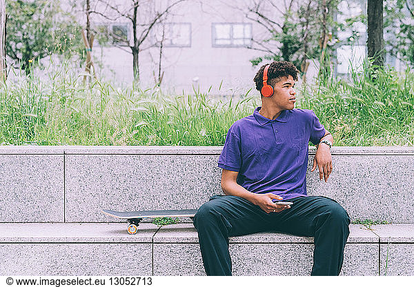Skateboarder using headphones on concrete bench  Milan  Italy