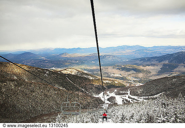 Ski lift over mountain against cloudy sky