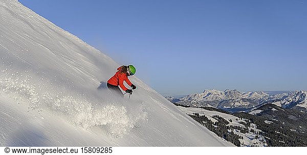 Skier going down steep slope  black piste  blue sky  mountains behind  SkiWelt Wilder Kaiser  Brixen im Thale  Tyrol  Austria  Europe